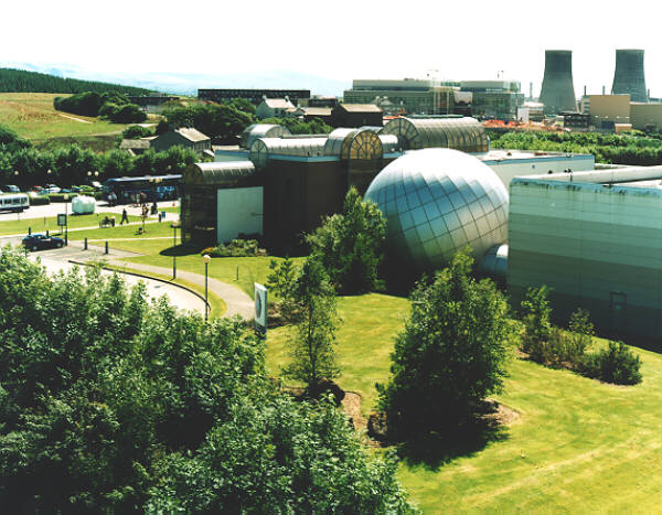 A sky view of the Sellafield Visitors Centre with the Calder Hall cooling towers behind it.