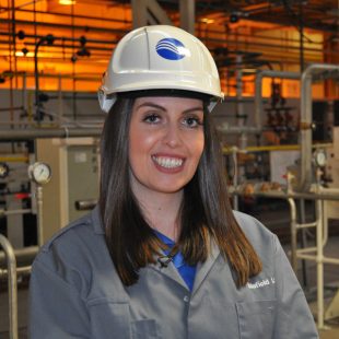 Jade White, wearing a hard hat and overall with the Sellafield Ltd logo on it.