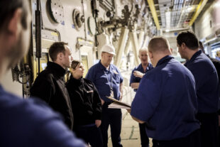 A group of Sellafield Ltd employees standing around having a conversation in a nuclear facility