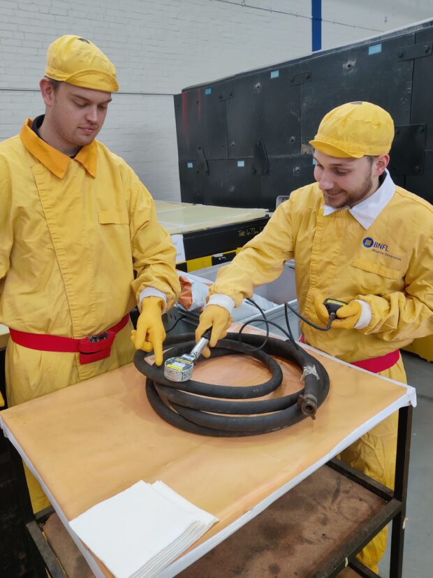 Joshua Bettles in PPE carries out a monitoring task under observation from a supervisor during his work placement at Sizewell A