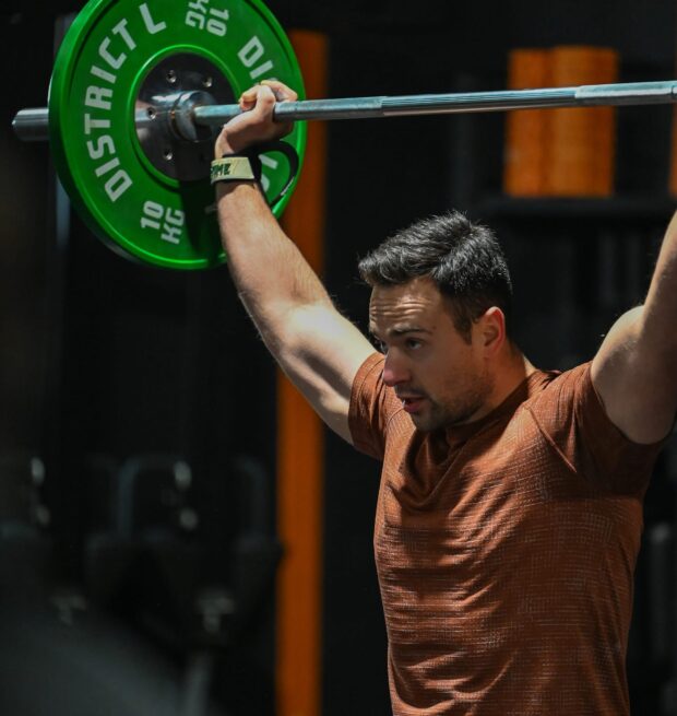 Man in t-shirt lift barbell above head